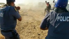 Police fire at striking miners outside a South African mine owned by Lonmin's of London