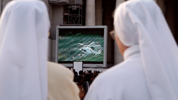 Nuns in Saint Peter's Square in Vatican City watch a giant screen of the helicopter carrying Pope Benedict XVI.