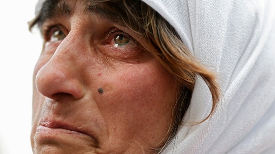 A woman cries as she watches the departure of Pope Benedict XVI on the giant screen.