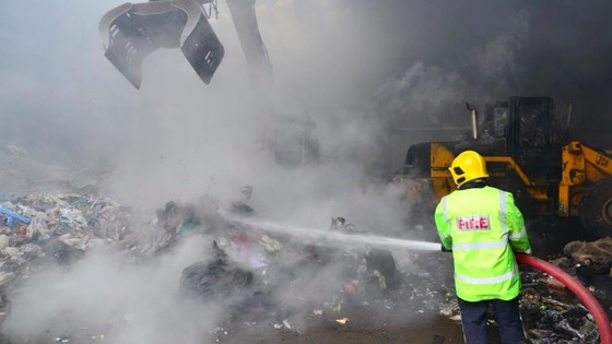 A firefighter douses burning rubbish at the site in Bickershaw