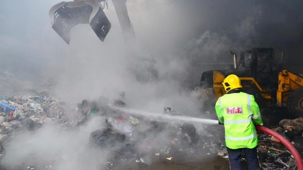 A firefighter douses burning rubbish at the site in Bickershaw