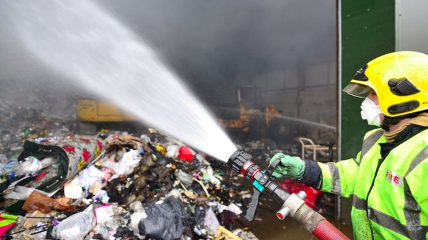 A firefighter douses the 76 tonnes of waste