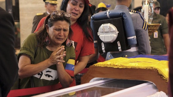 Mourners cry as they pay their respects as the body of Hugo Chavez lies in state