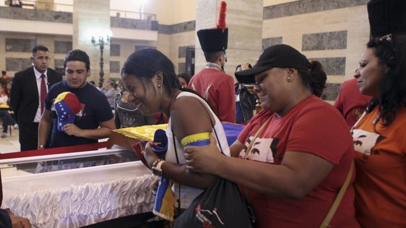 A woman is comforted as the body of Hugo Chavez lies in state