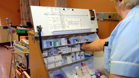 A member of the nursing staff dispensing drugs from a trolley on a ward