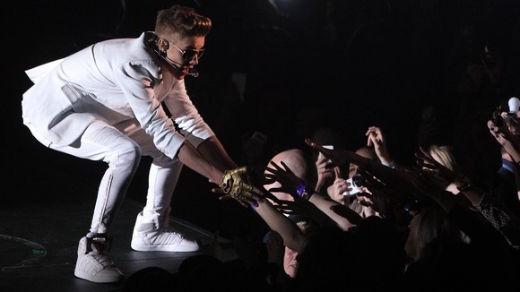 Justin Bieber greets fans on stage at the O2 Arena in London after appearing up to two hours late