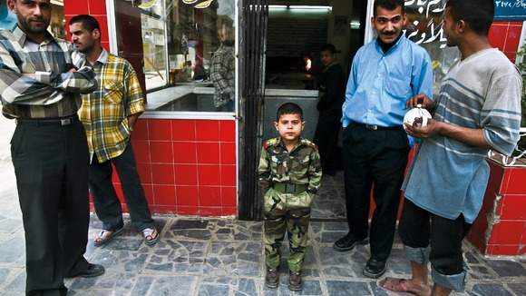 An Iraqi boy dressed as a soldier shows his family’s support for Saddam Hussein, Baghdad, 2003