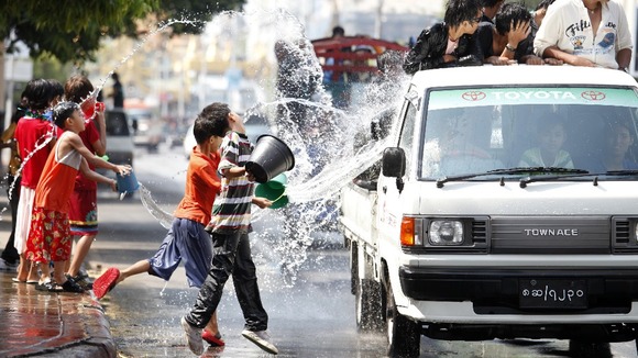 Children throw water at passing traffic in central Yangon