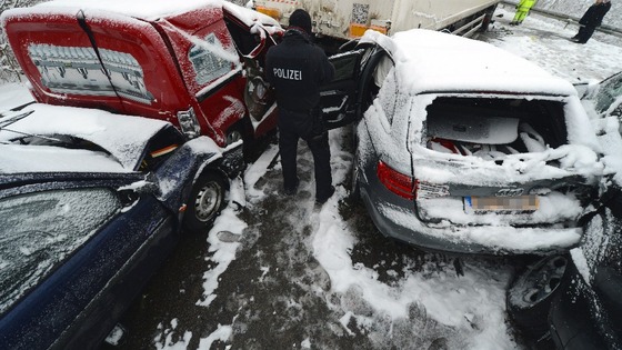 A police officer stands among the wrecked vehicles.