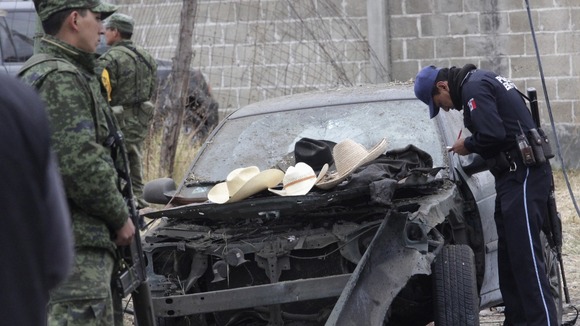 Soldiers and police inspect the site of an explosion.