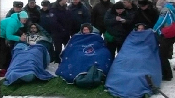 NASA's Kevin Ford and Russian cosmonauts Oleg Novitskiy and Evgeny Tarelkin wrapped in blankets after leaving the Soyuz space capsule