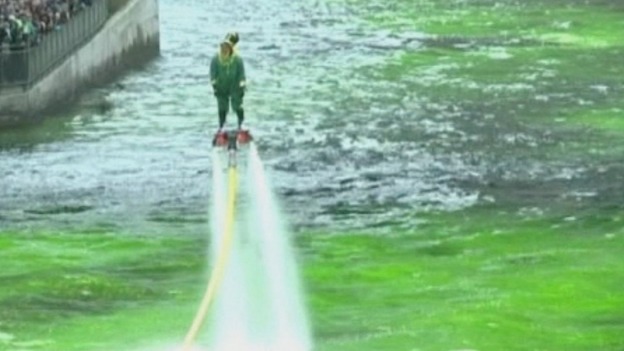 A man dressed as a leprechaun hovers over the Chicago River.