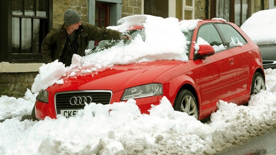 A man clears of the snow of his car in Bowes County Durham