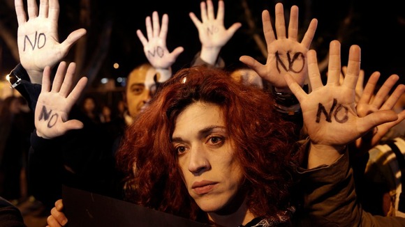 Anti-bailout protesters raise their open palms showing the word "No" after Cyprus' parliament