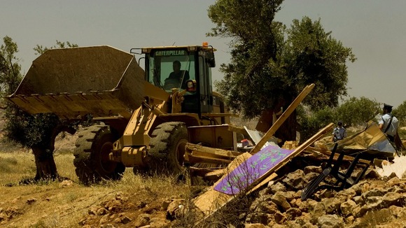 A bulldozer drives past a demolished makeshift structure in the unauthorised outpost of Ramat Migron