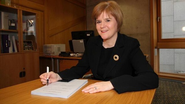 Nicola Sturgeon smiles as she signs the Bill.