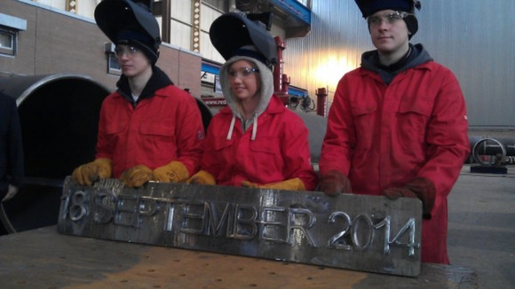 The apprentices hold up their handy work with the referendum date etched in steel.