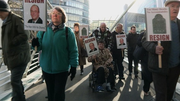 Crowd walking on bridge with placards