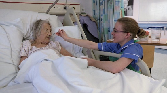 Nurse feeding old lady in hospital bed