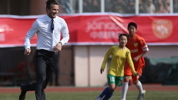 David Beckham plays football on a sports field during his visit in Qingdao