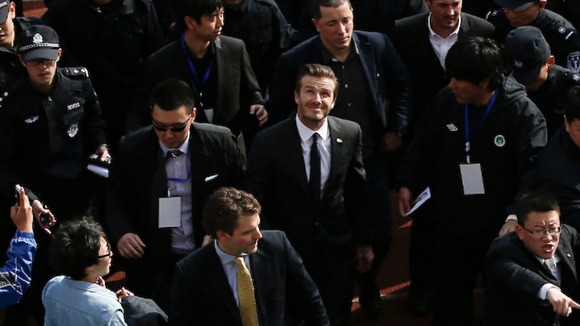 David Beckham makes his way into a sports field with help of security personnel