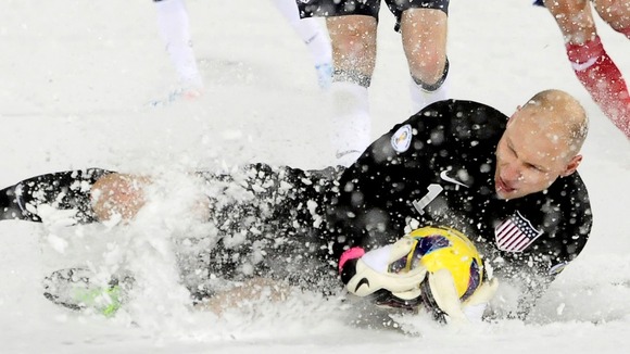 Brad Guzan of the US makes a sliding stop in the snow