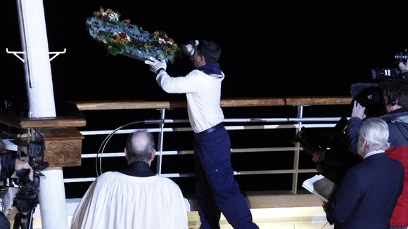 A crew member throws a wreath overboard during a memorial service, marking the 100th year anniversary of the Titanic disaster.