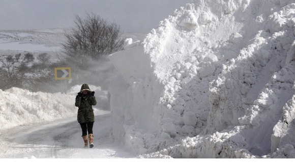 A person walks past a snow drift in the Glens of Antrim as wintry weather continues to cause havoc.