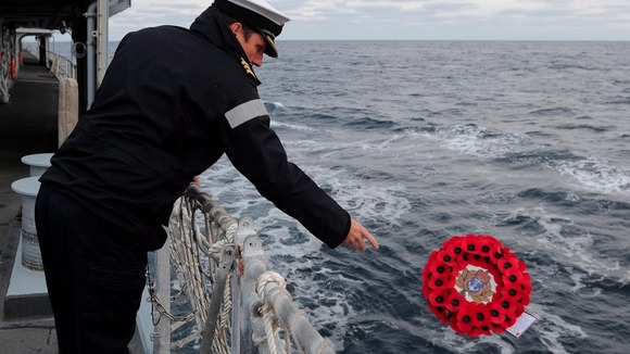 A sailor on the HMS Edinburgh lays a wreath in the mid Atlantic in memory of HMS Beverley