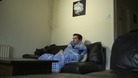 Man sits on sofa wrapped in blanket