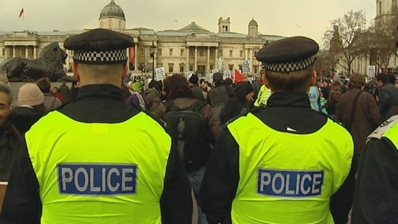 Police officers stand guard as protesters gather at London's Trafalgar Square.