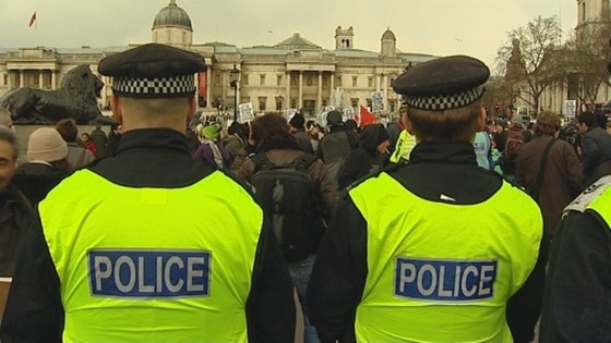 Police officers stand guard as protesters gather at London's Trafalgar Square.