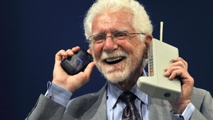 Martin Cooper holds the Motorola DynaTAC phone, the world's first commercial handheld cellular phone and a more recent model.
