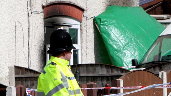 Police guarding the burnt out home of Mick Philpott last year