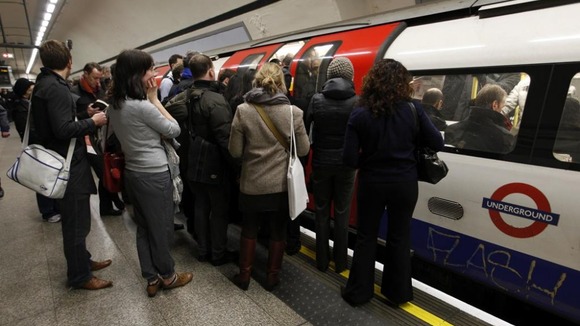 Passengers try to get on board a crowded tube train.