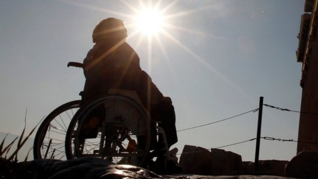 A person sitting in a wheelchair facing the sun.