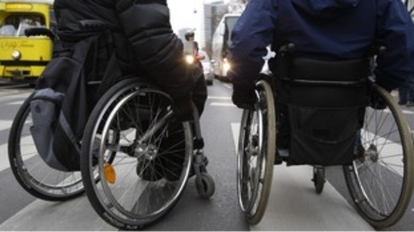 Two people in wheelchairs crossing the road.