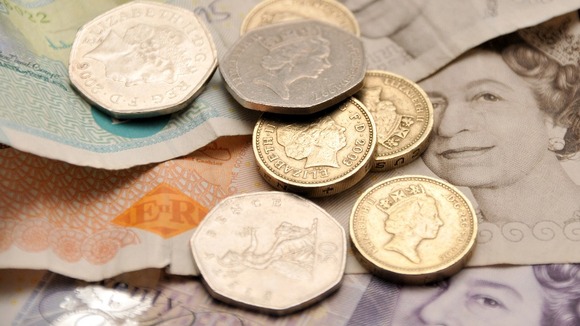 English coins on a backdrop of five, ten and twenty pound notes.