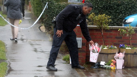 A police officer places flowers at the property Ruislip, northwest London.