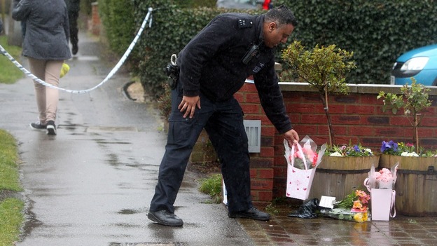 A police officer places flowers at the property Ruislip, northwest London.