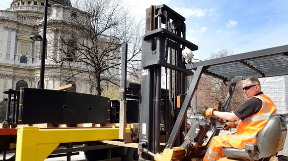 A fork-lift driver unloads steel road barriers that will be used in the ring of security around St. Paul's for Baroness Thatcher's funeral.