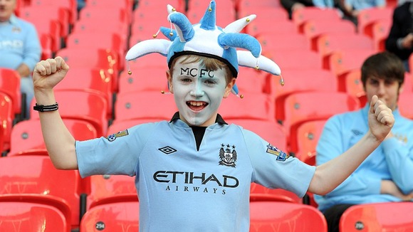 A young Manchester City fan cheers on his team in the stands