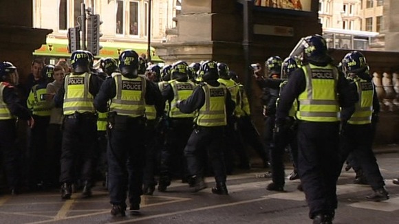 Police in riot gear run to hold barricade after the derby match.