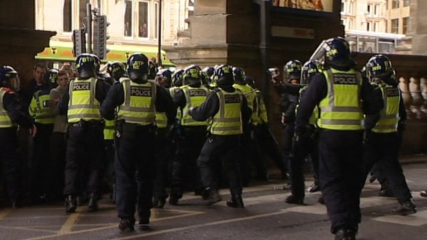 Police in riot gear run to hold barricade after the derby match.