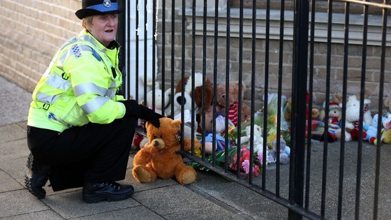 A PCSO lays a tribute from a member of the public outside a flat in Lowestoft