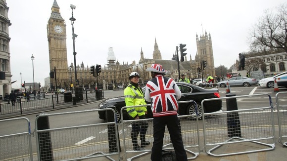 A spectator sporting a Union Flag hat and coat speaks to a police officer at Parliament Square.