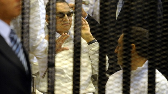 Hosni Mubarak waves as he sits behind bars during a hearing in his retrial last week.