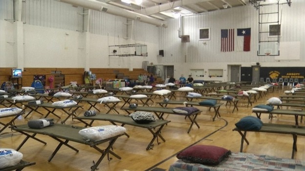 Camping beds lined up in the gym at Abbott High School