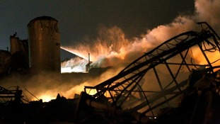 Smoke rises as water is sprayed at the burning remains of the fertilizer plant