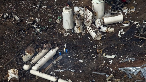 Investigators stand amid the aftermath of the massive explosion